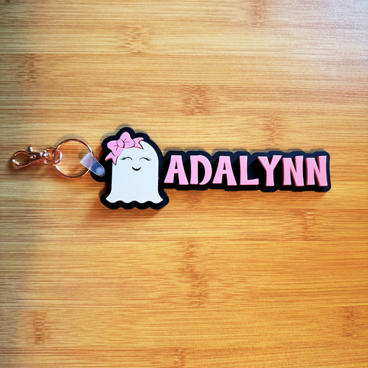 Ghost keychain with 'ADALYNN' text on a wooden surface