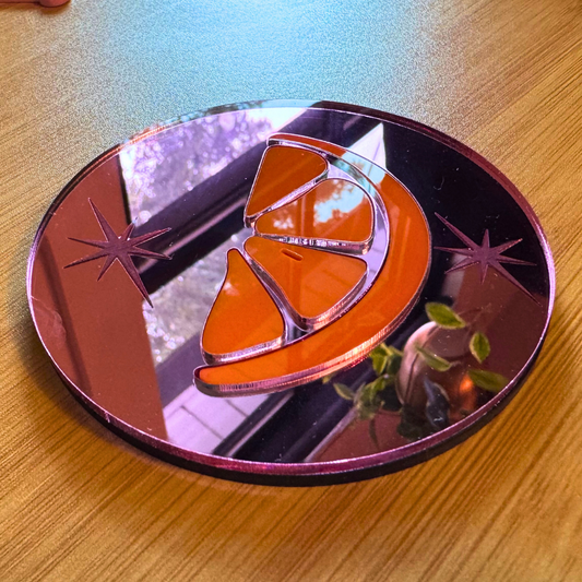 an orange slice inlaid in pink mirror acrylic