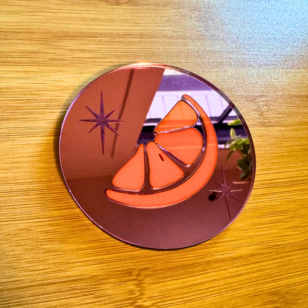 an orange slice inlaid in pink mirror acrylic