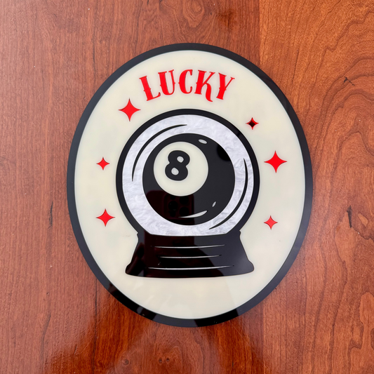 Decorative plate with an eight-ball design and 'LUCKY' text on a wooden surface