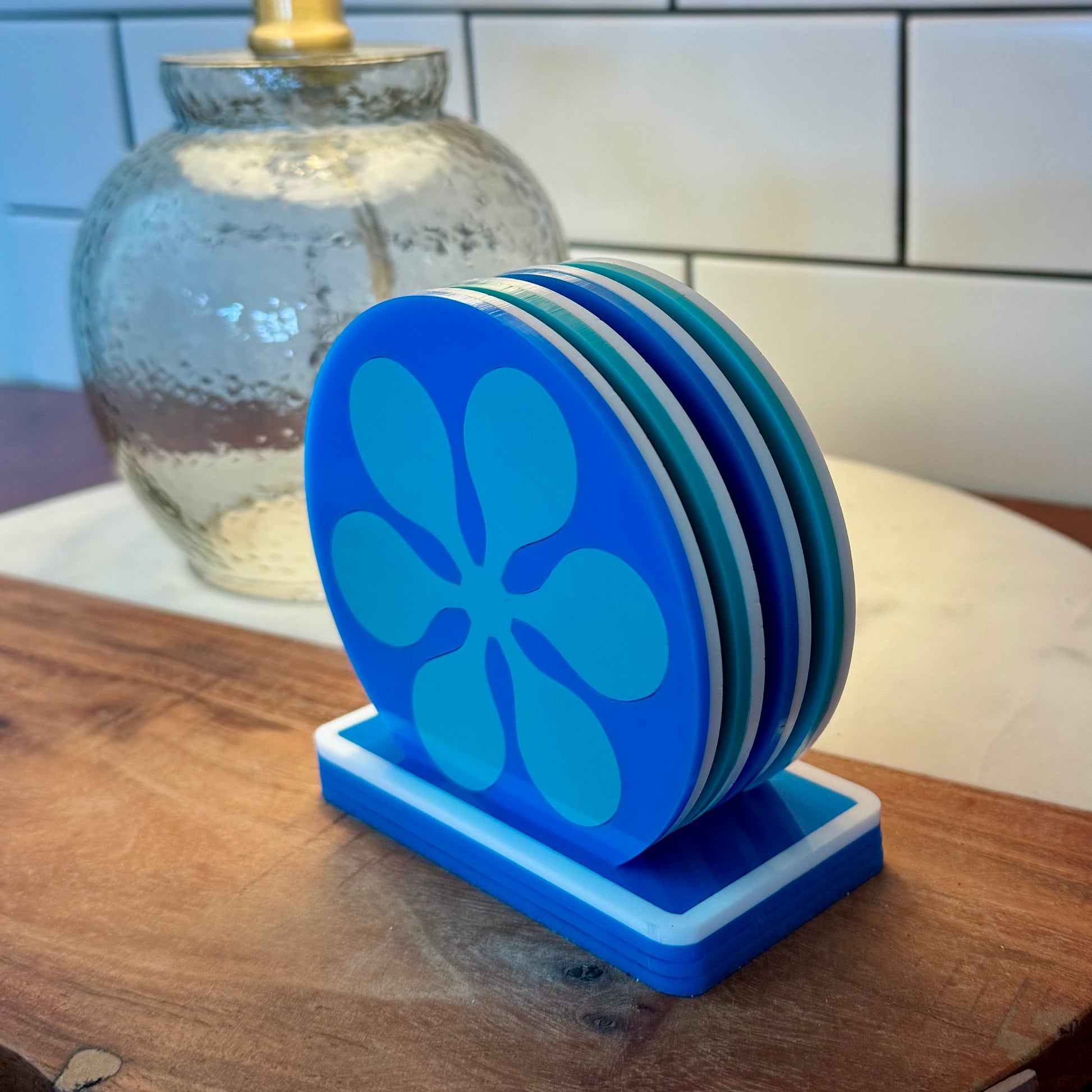 Stack of blue coasters with a mid century floral design on a wooden surface