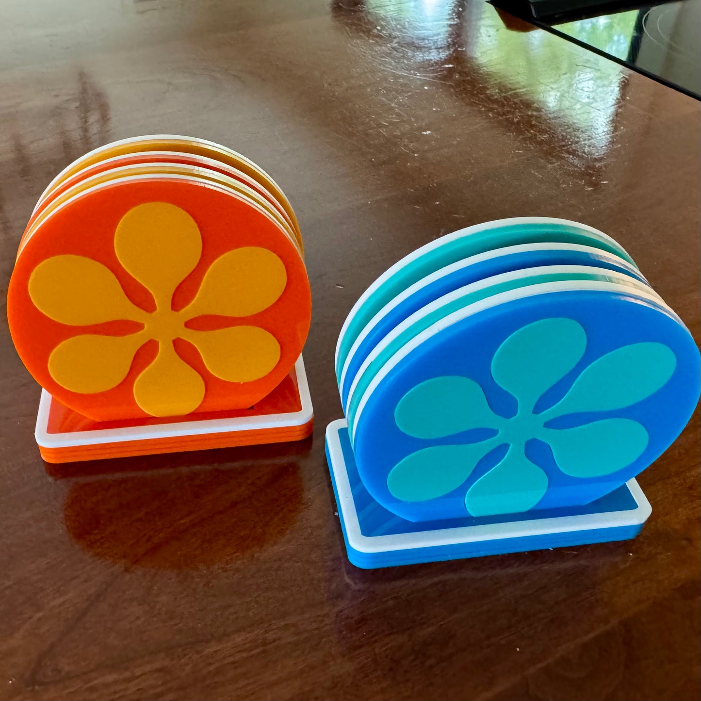 Stack of orange and blue coasters with floral design on a wooden surface