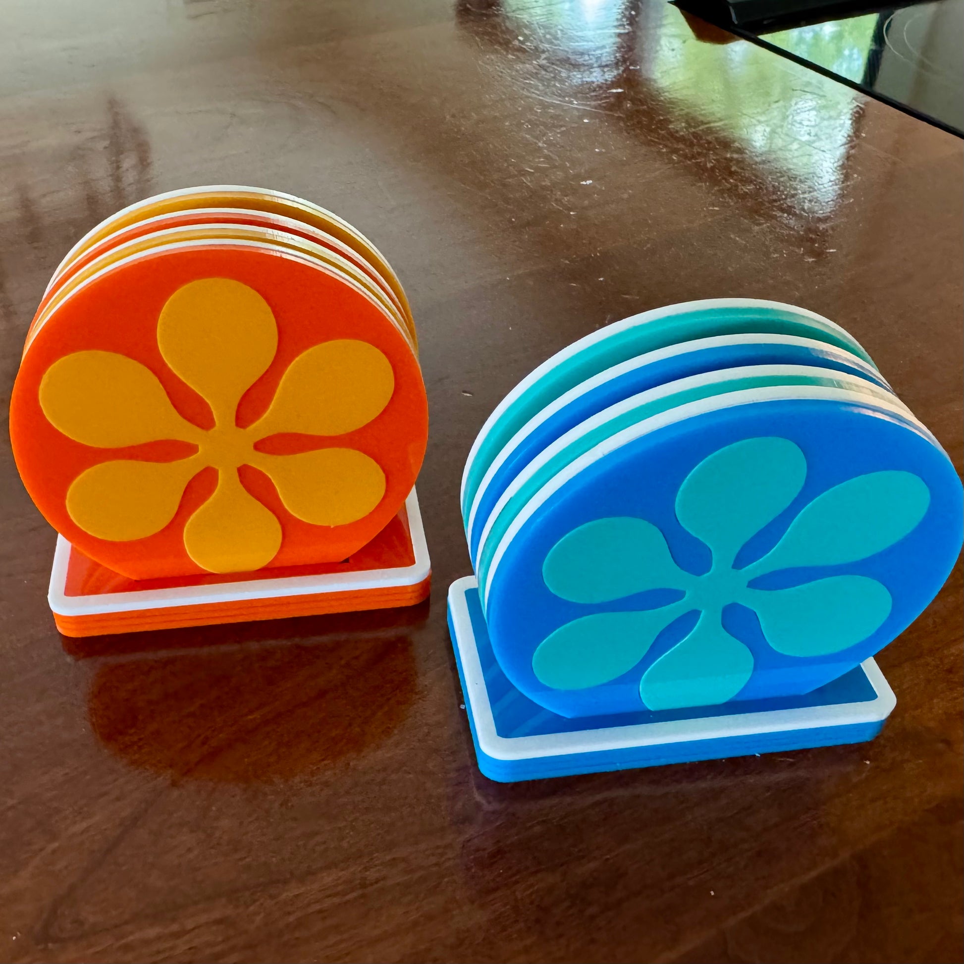 Stack of orange and blue coasters with floral design on a wooden surface