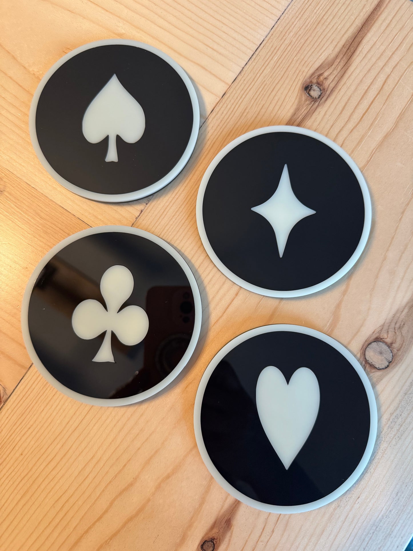 Four black coasters with white symbols on a wooden surface