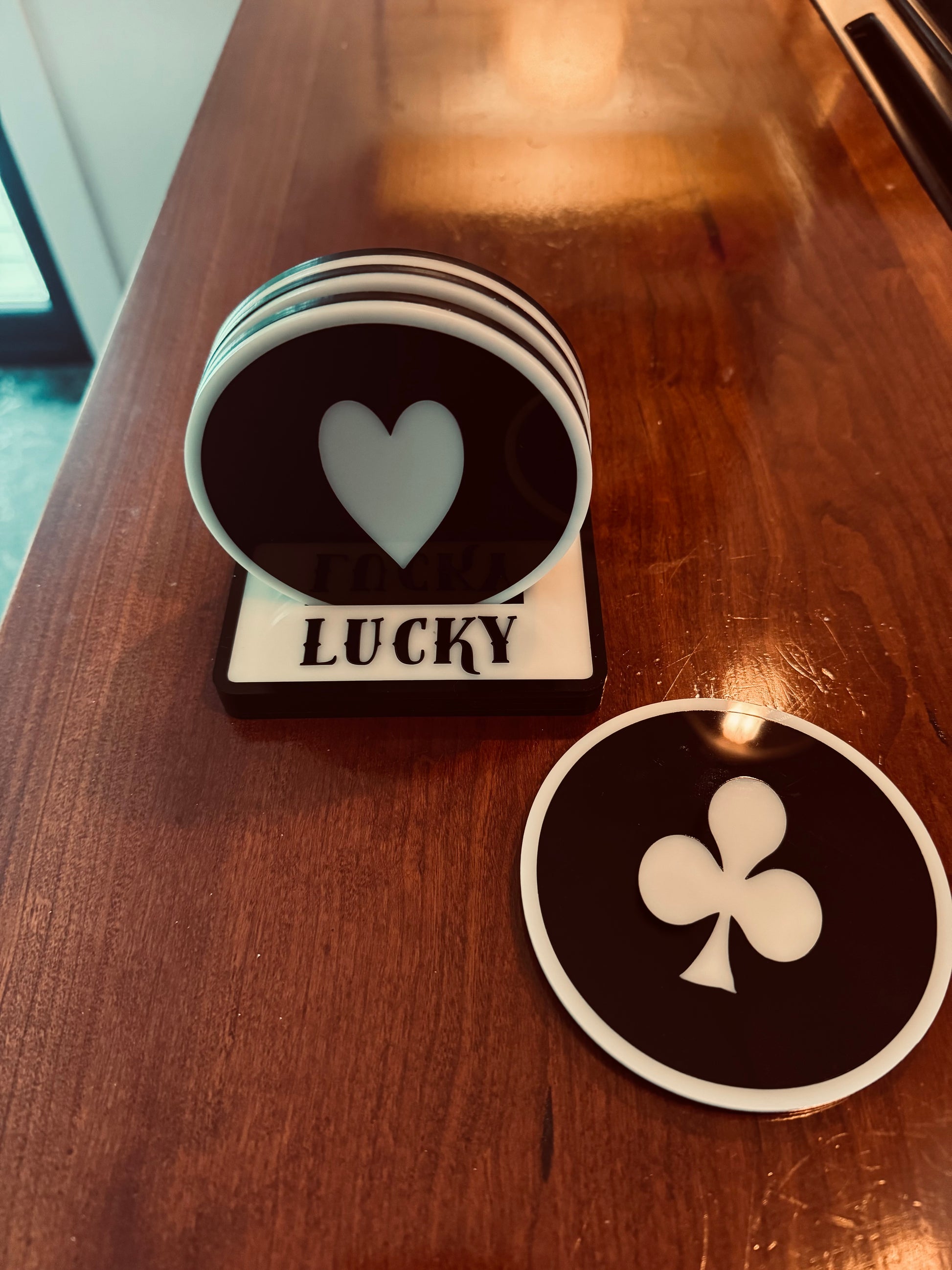 Two coasters with heart and club symbols on a wooden surface