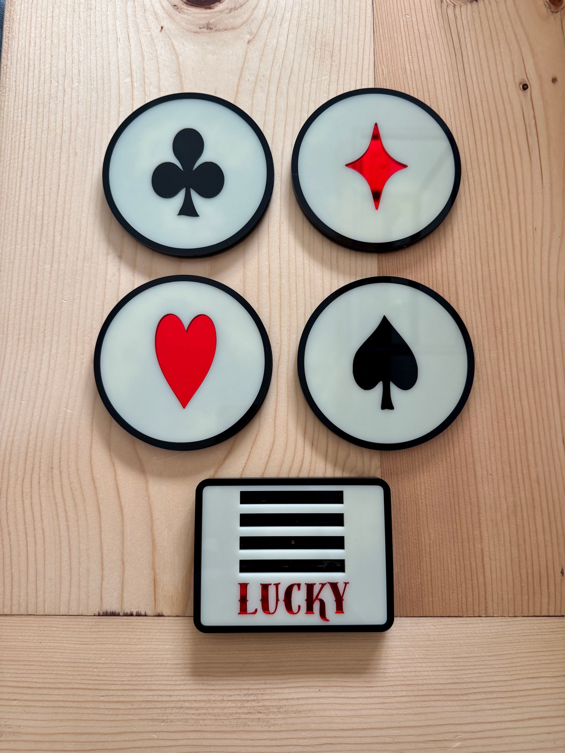 Four round patches with card suit symbols and a square 'LUCKY' patch on a wooden surface.