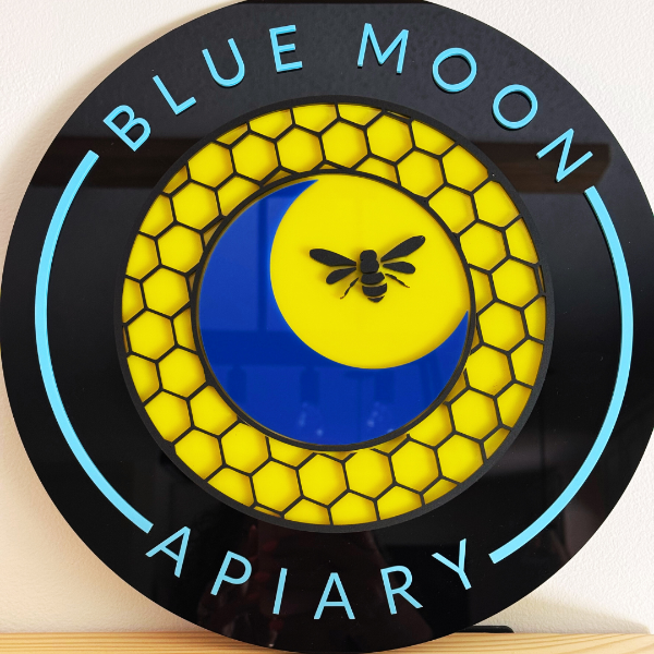 Decorative sign with 'Blue Moon Apiary' logo featuring a bee and honeycomb design.