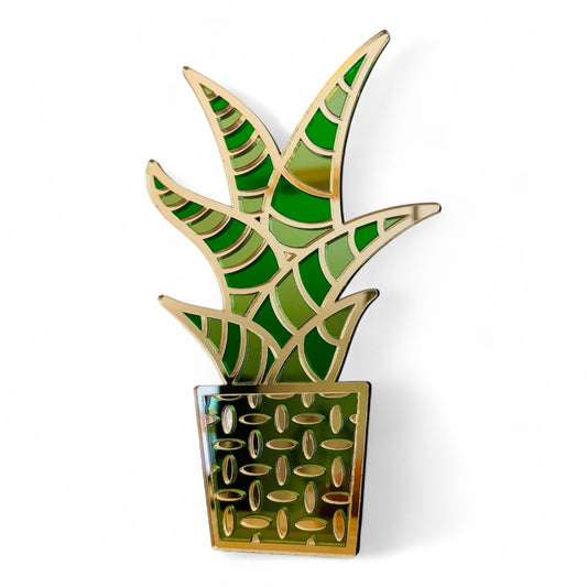 Decorative plant-shaped acrylic object with green and gold snake plant design on a white background