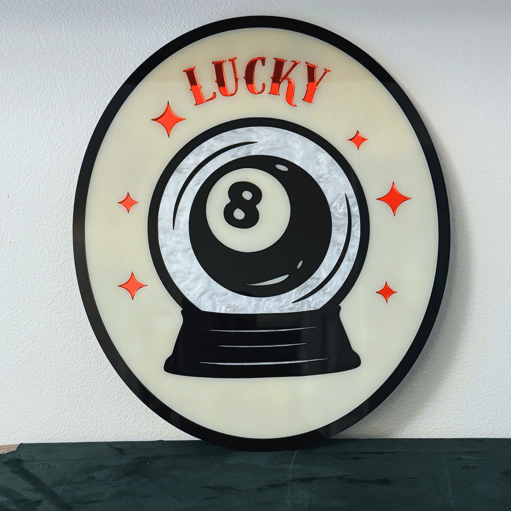 Decorative wall art with a black and white eight-ball design and 'LUCKY' text on a light background.